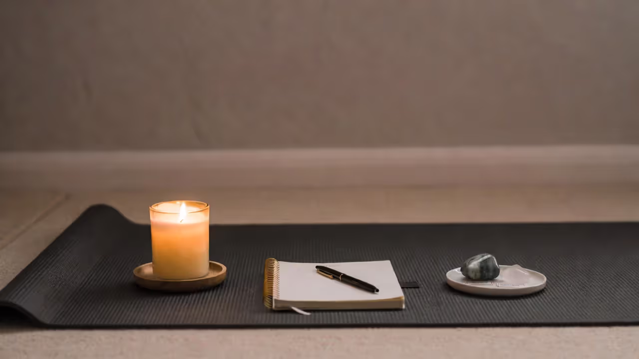 Yoga mat with a candle and journal set up for a simple full moon yoga ritual at home.